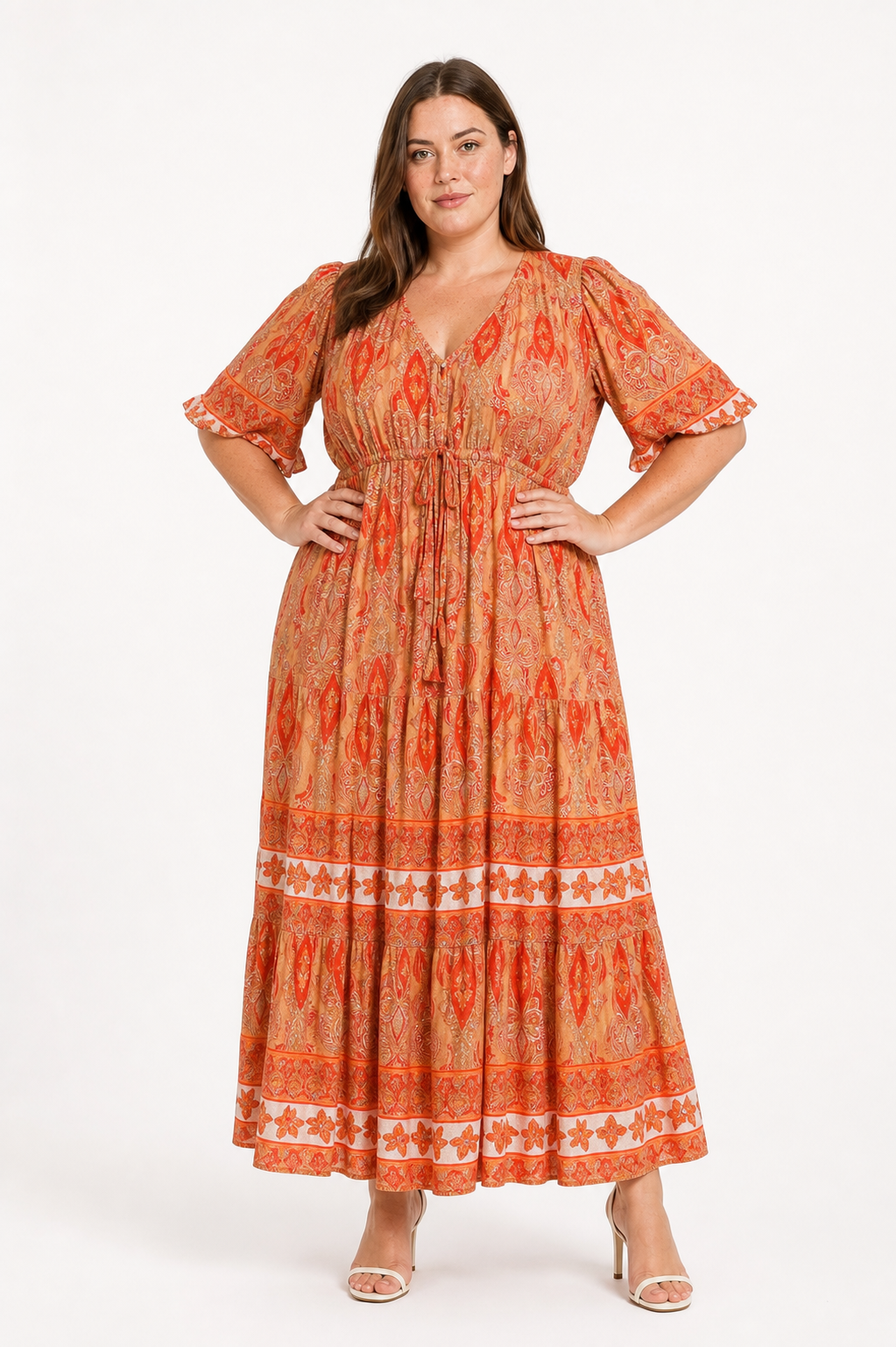 Jia wearing the Rosie Maxi in an apricot orange paisley print, front view with hands on hips