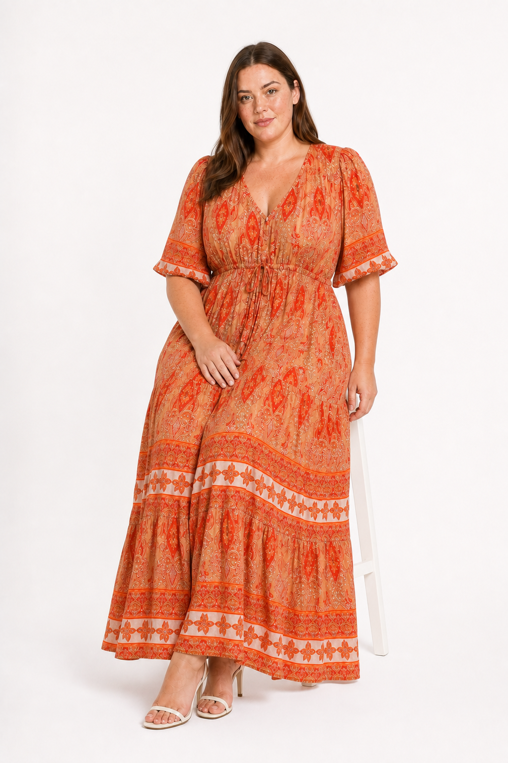 Jia seated in the Rosie Maxi in an apricot orange paisley print